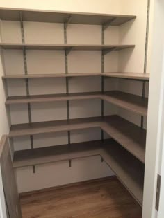 an empty walk in closet with shelves and wood floors