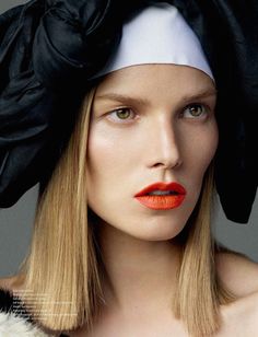 a woman with red lipstick and a black hat on her head is photographed in this image