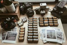 an assortment of old cameras and batteries on a table next to a bottle of wine