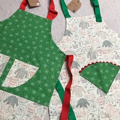 two aprons are sitting on the table next to each other, one is green and white