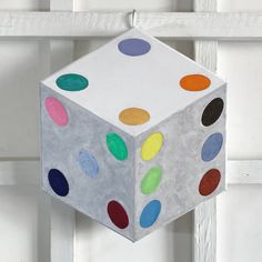 a paper cube with colored dots hanging from it's side on a white door