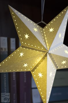 a gold and white paper star hanging from a book shelf