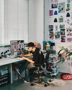 a young man sitting at a desk in front of a computer monitor and writing on a piece of paper