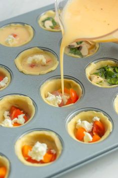 someone is pouring sauce on some cupcakes in a muffin tin filled with food