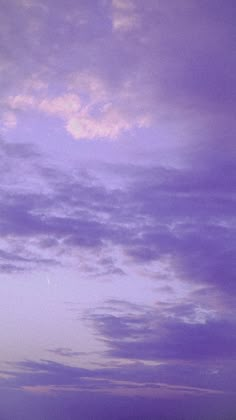 a plane flying in the sky at dusk with some clouds above it and an airplane on the ground