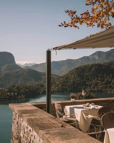 an outdoor dining area overlooking a lake with mountains in the background