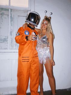 a man and woman dressed up as astronauts posing for the camera with an orange astronaut suit on