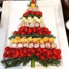 a christmas tree made out of cheese, tomatoes and other foods on a white plate