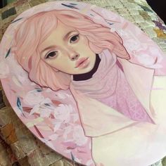 a painting of a woman with pink hair on top of a plate that is sitting on a bed