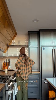 a person standing in a kitchen next to a stove top oven