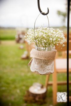 flowers are hanging from the back of a wooden chair at an outdoor wedding ceremony,