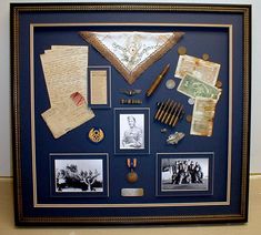 a framed display with many items and papers on the bottom shelf, including an old baseball cap