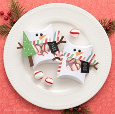 two paper snowmen on a plate with candy