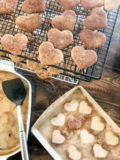 some heart shaped cookies are sitting in pans on a table next to a cooling rack