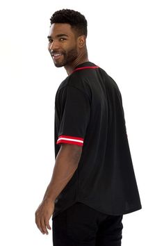 a man wearing a black shirt with red and white stripes on the sleeves is standing in front of a white background