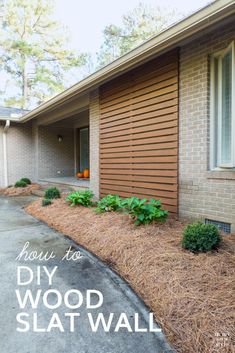 a house with wood slat siding on the side and plants growing in the front yard