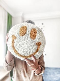 a woman holding up a smiley face pillow