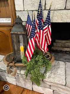 three american flags sitting on top of a mantle next to a candle and potted plant