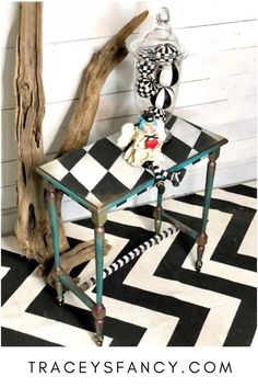 a small table with a checkered design on it and a glass vase next to it