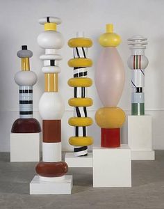 there are many different colored vases on this table top stand, including one with yellow and white stripes