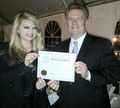 a man and woman standing next to each other holding up a certificate in front of them