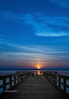 the sun is setting at the end of a pier