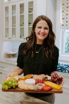 a woman holding a platter full of food in her hands and smiling at the camera