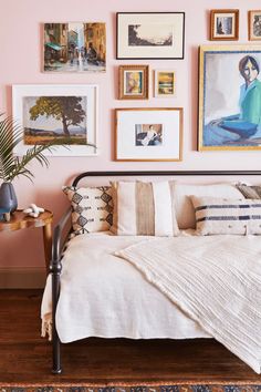 a bedroom with pink walls and pictures on the wall