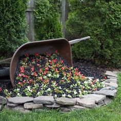 a wheelbarrow filled with dirt and flowers sitting in the middle of a garden