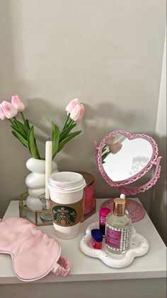 a white table topped with lots of beauty items next to a vase filled with tulips