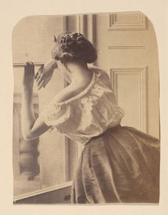 an old black and white photo of a woman looking out the window