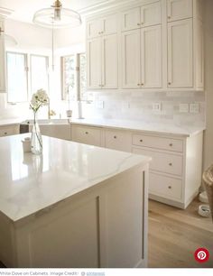 a large white kitchen with an island in the middle and lots of cabinets on both sides