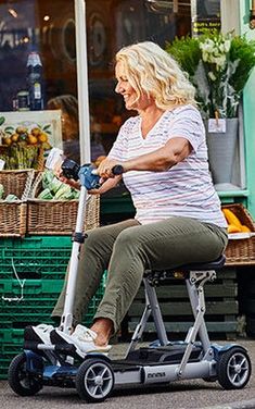 a woman is riding an electric scooter down the street in front of a store