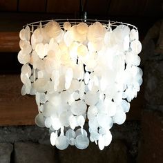 a white chandelier hanging from a ceiling in a room with stone walls and wood beams