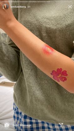 a woman with a flower tattoo on her arm and hand is taking a selfie