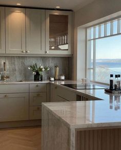 a large kitchen with marble counter tops and white cabinetry, along with an ocean view