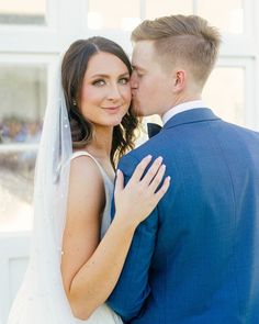 a bride and groom embracing each other in front of a white building with large windows