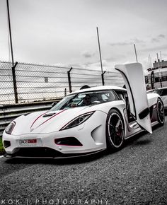 two white sports cars parked next to each other on the side of a race track