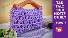 a purple crochet purse sitting on top of a table next to a flower