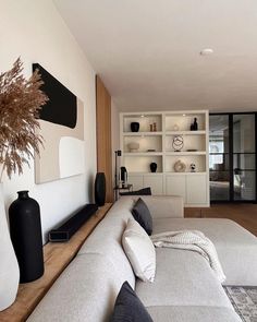 a living room filled with lots of furniture next to a tall white vase on top of a hard wood floor