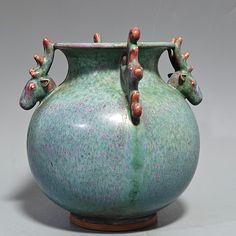 a green vase with two giraffes sticking out of it's sides