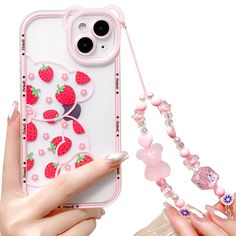 a woman holding up a phone case with strawberries on it and beads hanging from the back