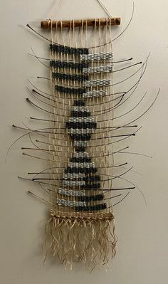 a wall hanging made out of woven material and wood sticks with thread on the sides