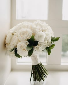 a bouquet of white flowers sitting on top of a table next to a windowsill