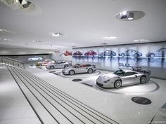 several cars are on display in a showroom with white tile flooring and round lights