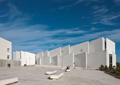 an empty parking lot in front of several white buildings with stairs leading up to them