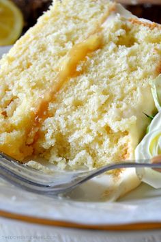 a slice of lemon cake on a plate with a fork and some flowers next to it