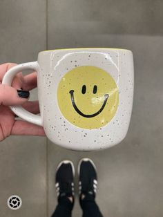 a person holding a coffee mug with a smiley face painted on it