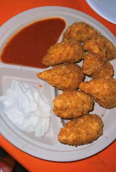 some fried food is on a plate with sauce and mayonnaise next to it