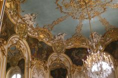 an ornately decorated room with chandeliers and paintings on the walls in gold